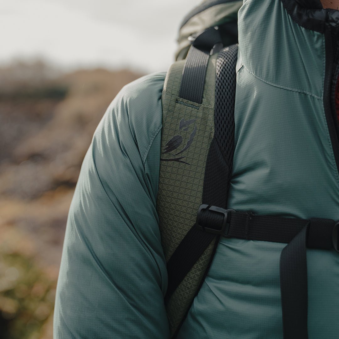 A close-up of hands adjusting the straps on a wheeled hybrid travel bag.