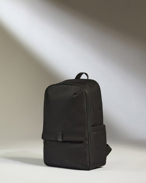 A traveler sitting in an airport lounge with their travel backpack nearby.