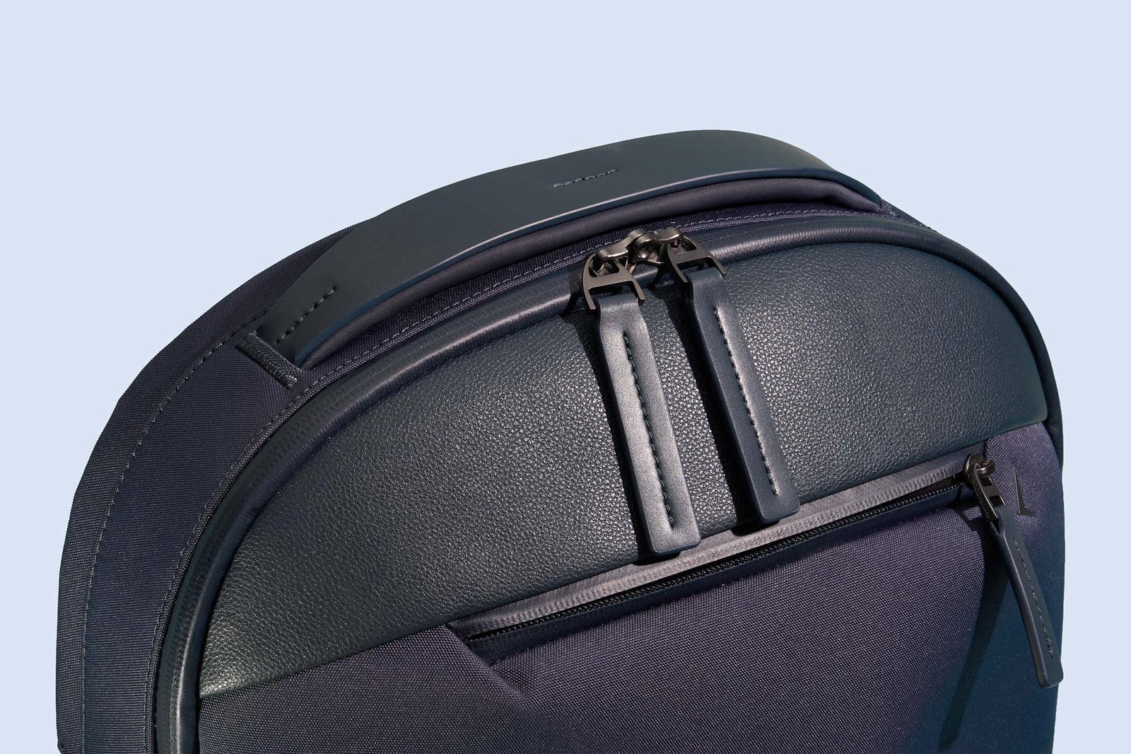 Three distinct laptop backpacks displayed side by side on a minimalist wooden bench.