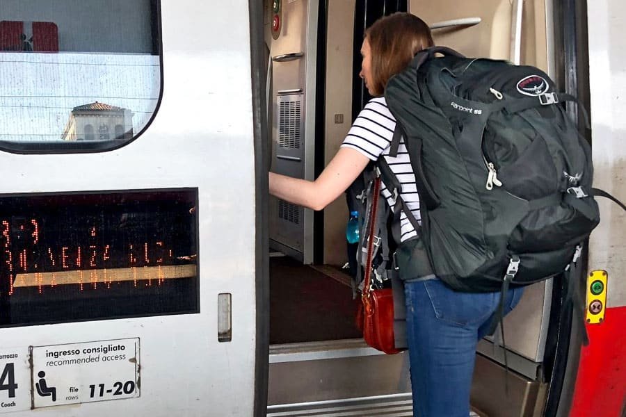 Hands tighten the compression straps on a large backpack to reduce its overall size.