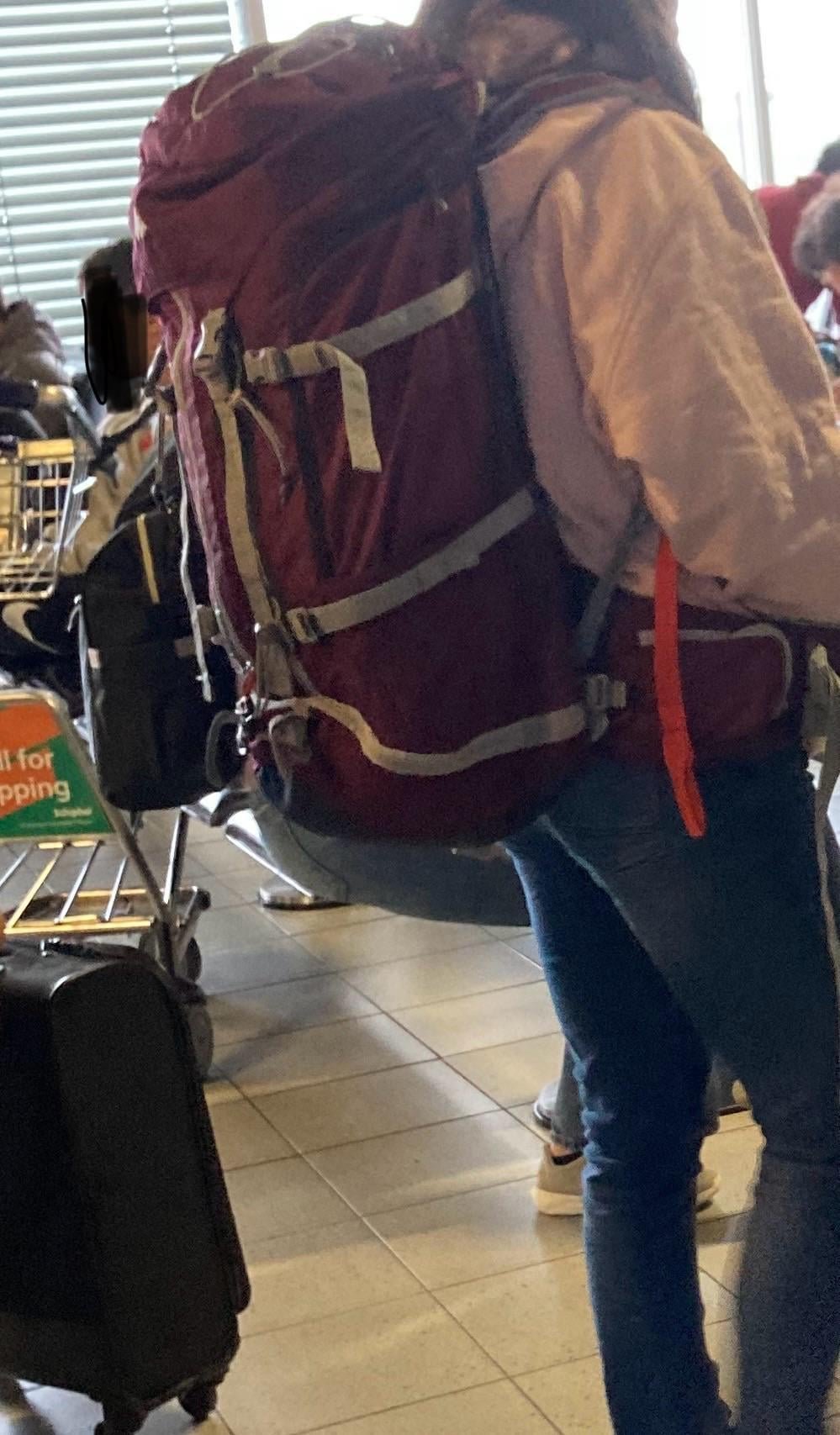 Hands tightening compression straps on a hiking backpack to prepare for carry on travel.