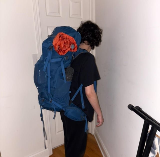 A laptop and an organized carry-on backpack on a desk during travel planning.