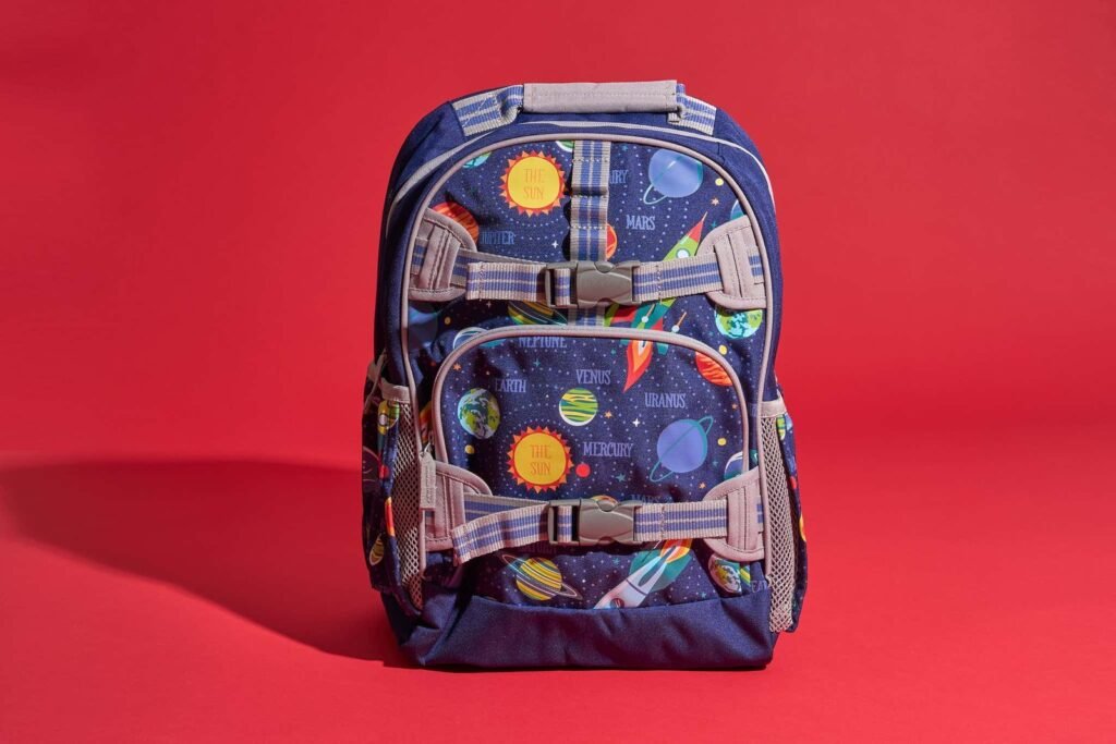 A colorful elementary school backpack sits in a sunlit hallway ready for class.