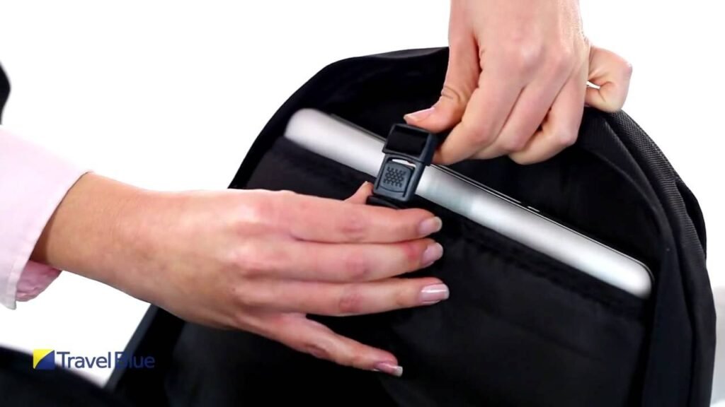 A person carefully sliding their laptop into a protective backpack sleeve in an office.