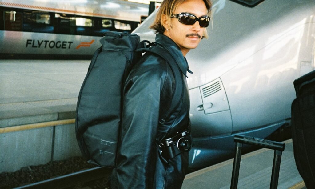 A durable travel backpack resting on a wooden bench inside a bright airport terminal.