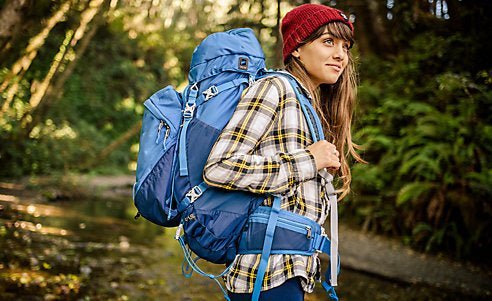 Hands tighten the compression straps on a travel backpack to secure the load.