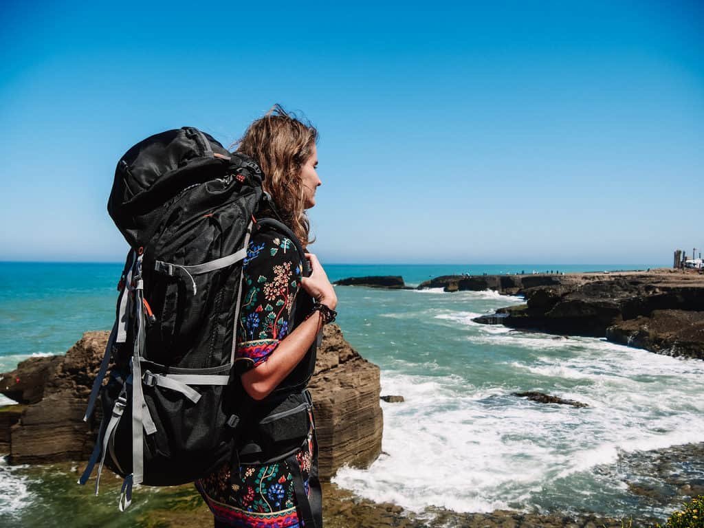 A traveler examining various styles of travel backpacks on a wooden table.