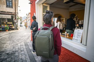 Two travelers with different backpacks navigate a train station for their upcoming trips.