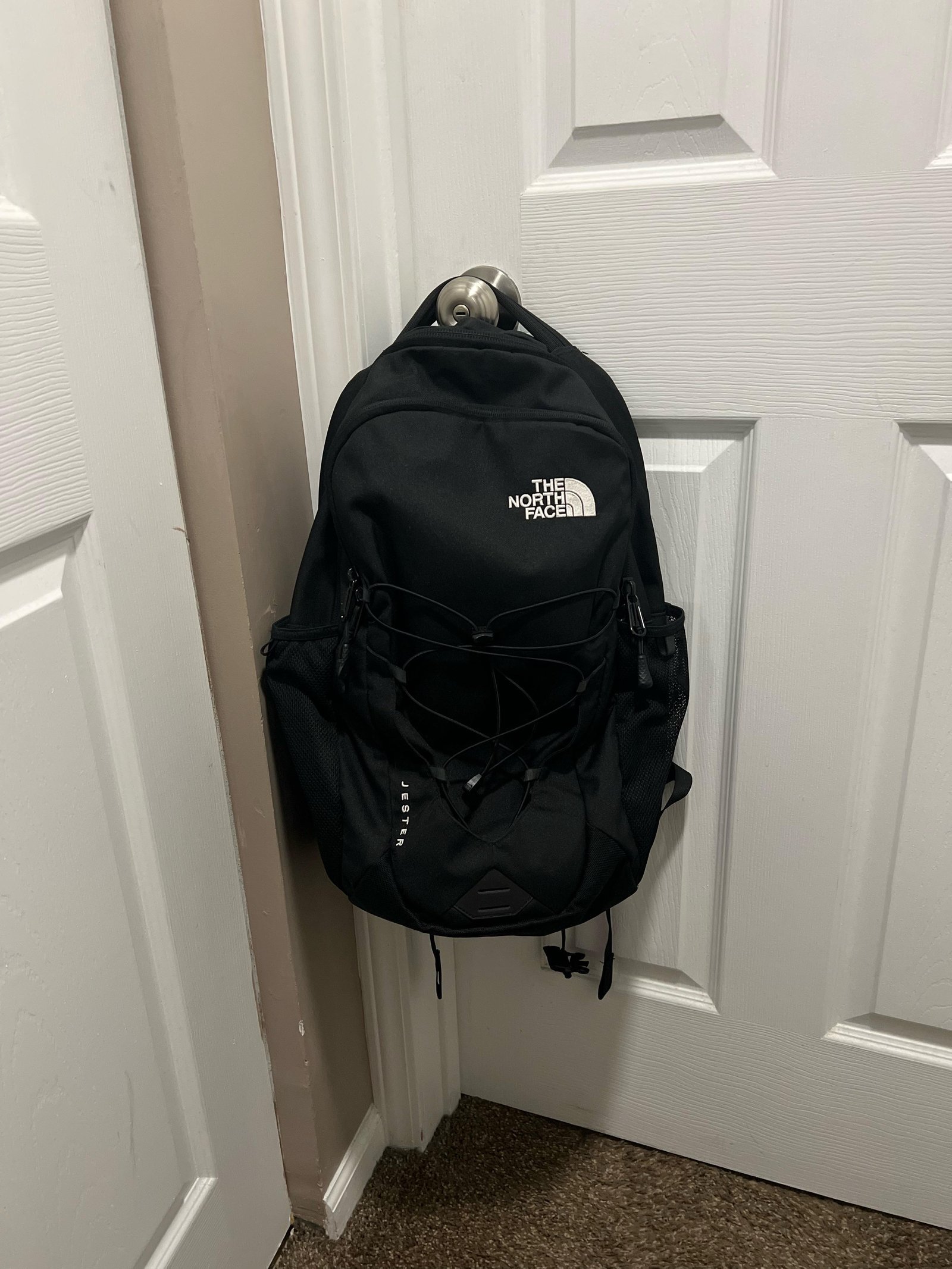 A laptop and a travel backpack arranged neatly on a wooden desk surface.