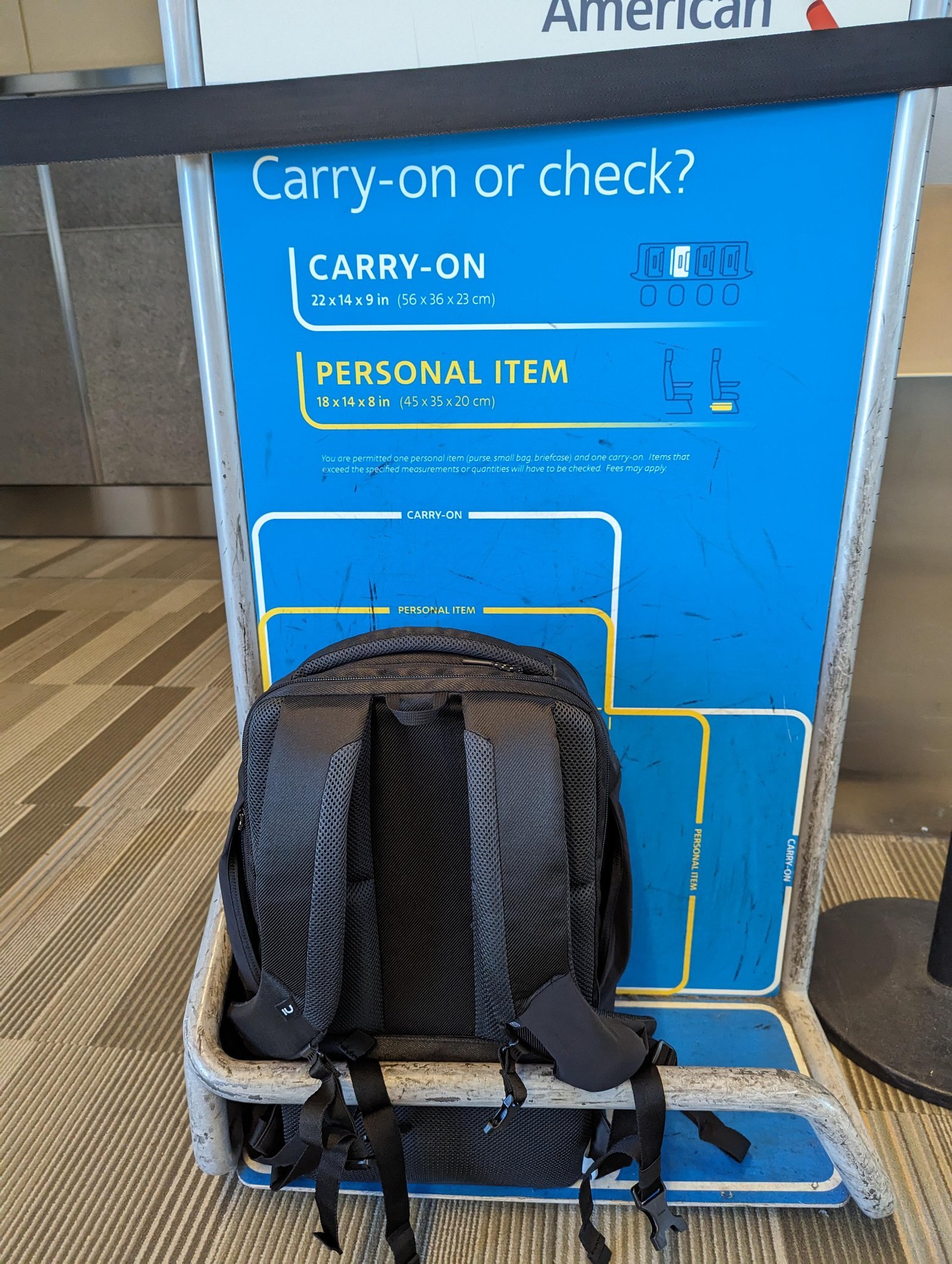 A traveler tests if their backpack fits inside an airline sizer frame.