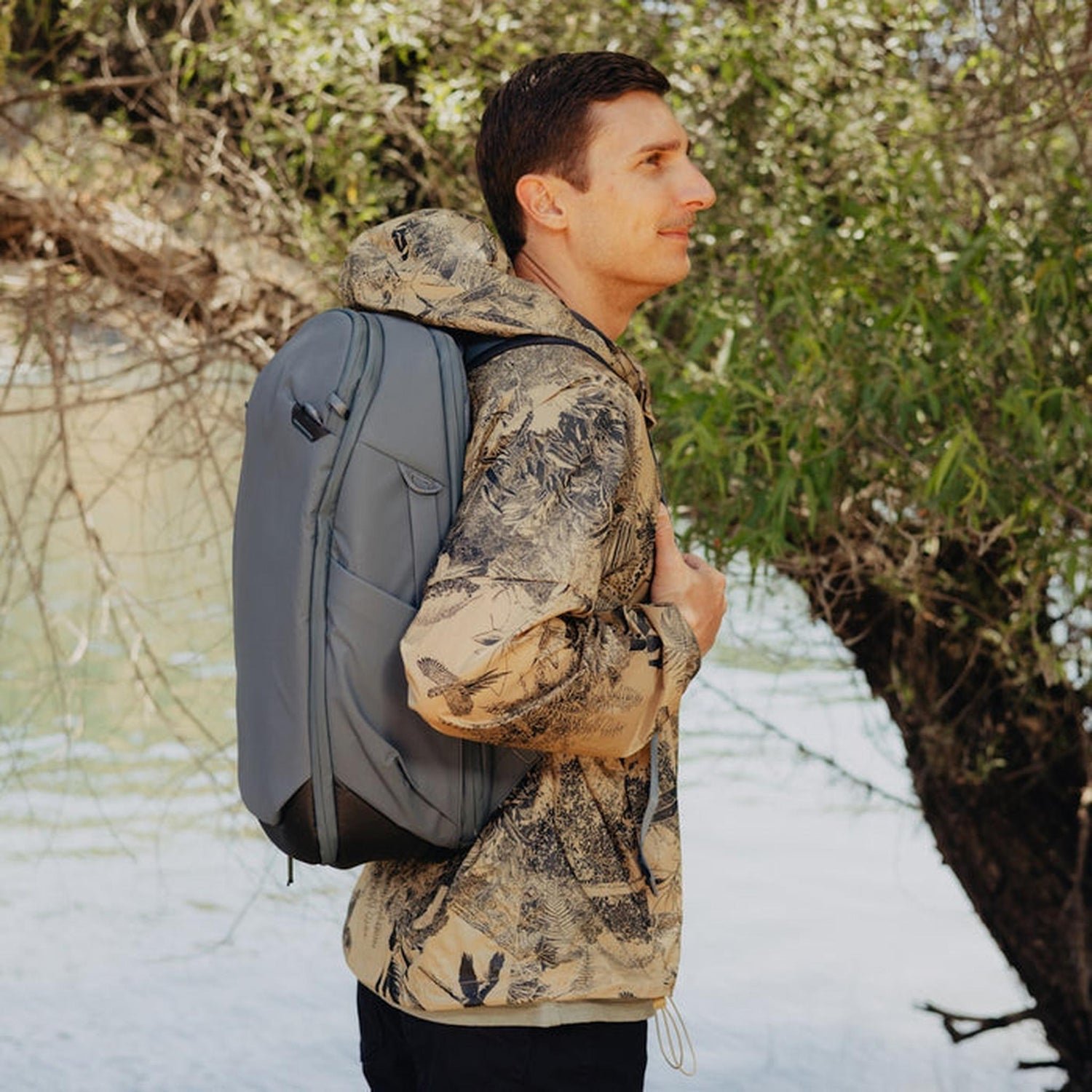 Traveler comparing a lifestyle backpack to a larger clamshell bag on a street.