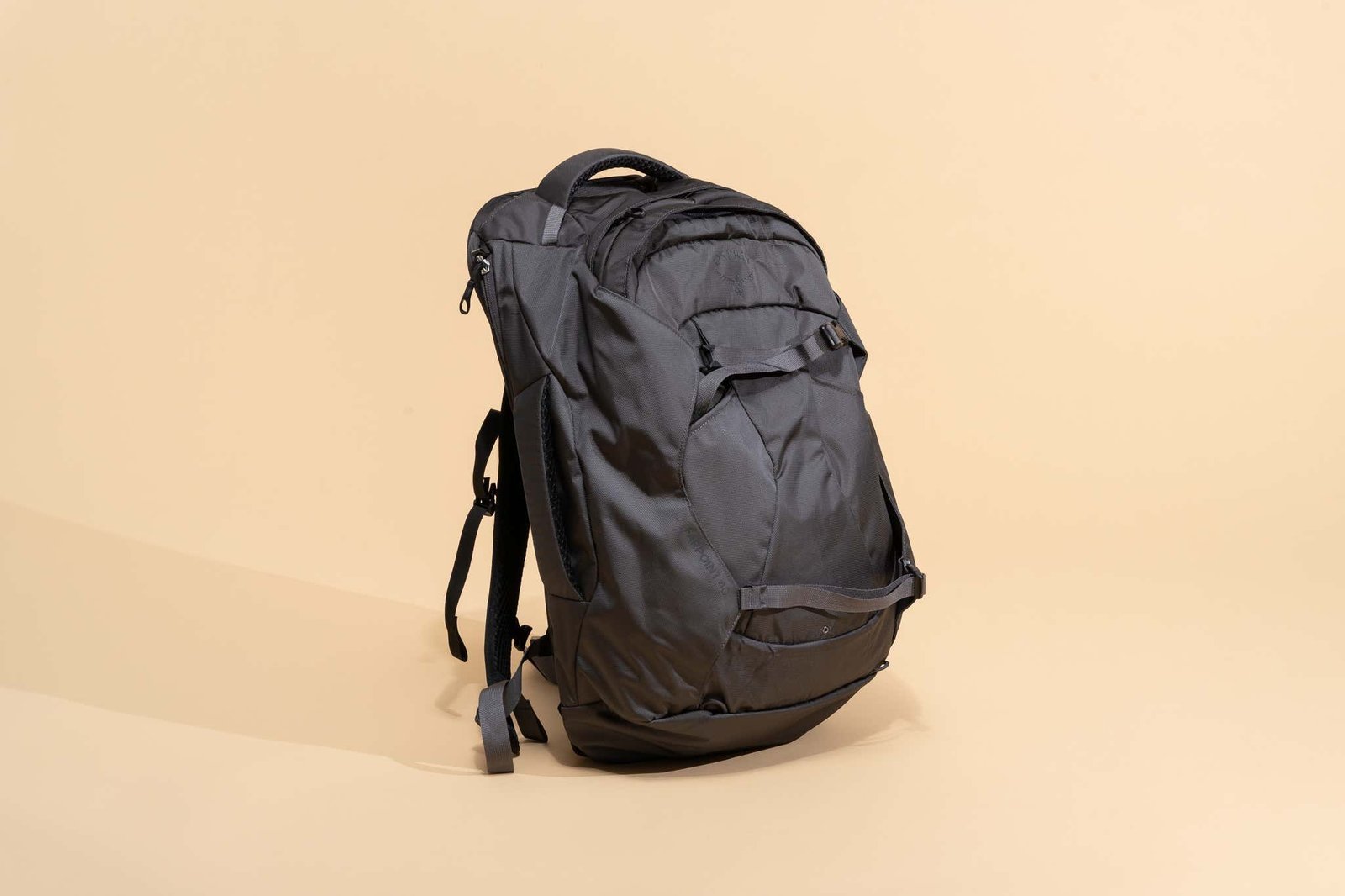 A lightweight travel backpack sits on a desk next to travel planning essentials and documents.