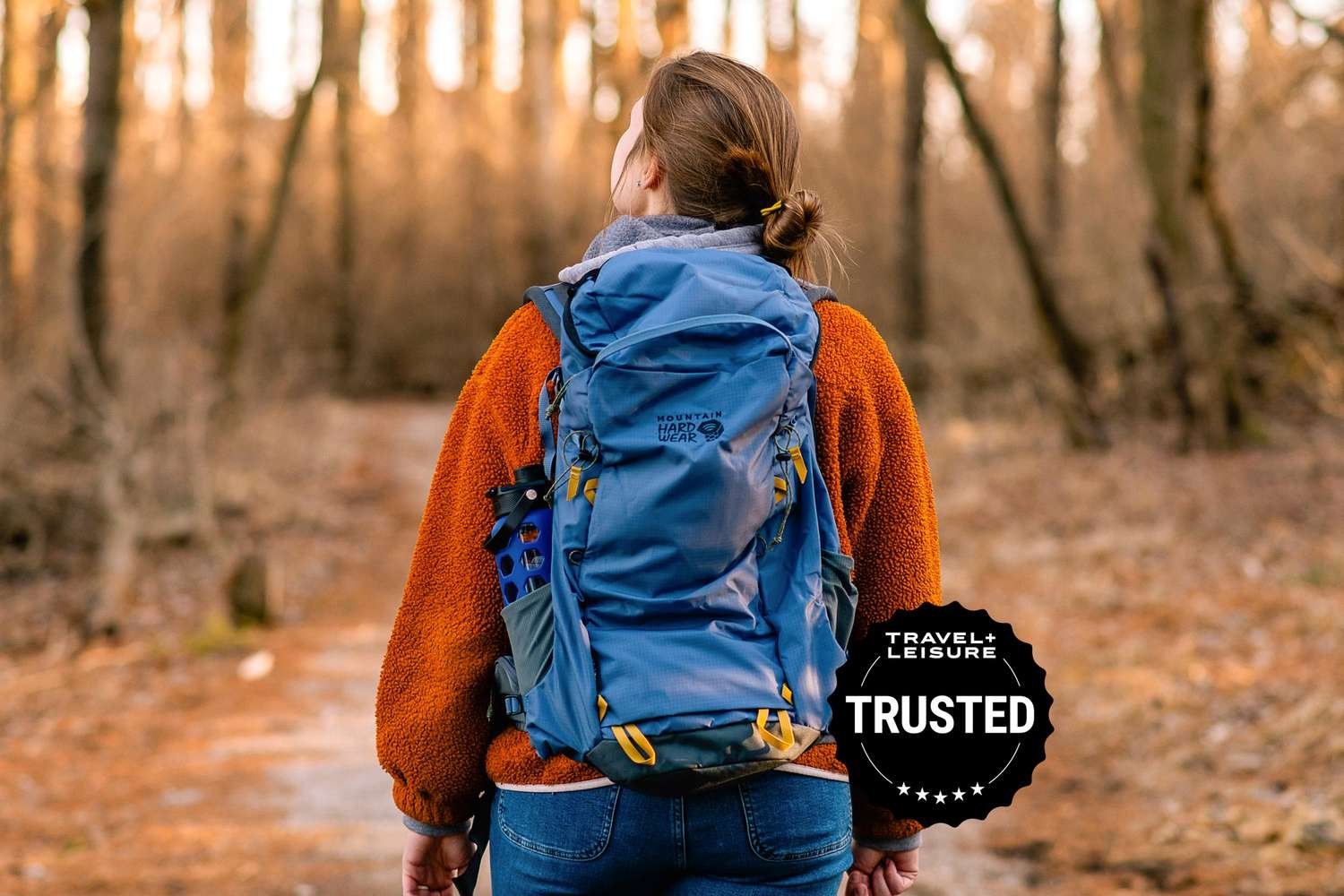 A traveler checking gear details while sitting with an outdoor travel backpack.