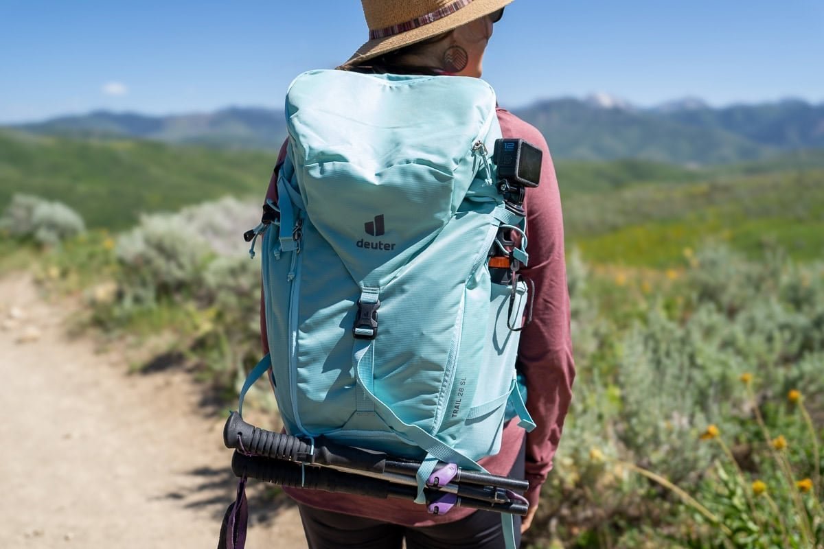 A hiker struggles with an improperly fitted and overloaded travel backpack on a trail.