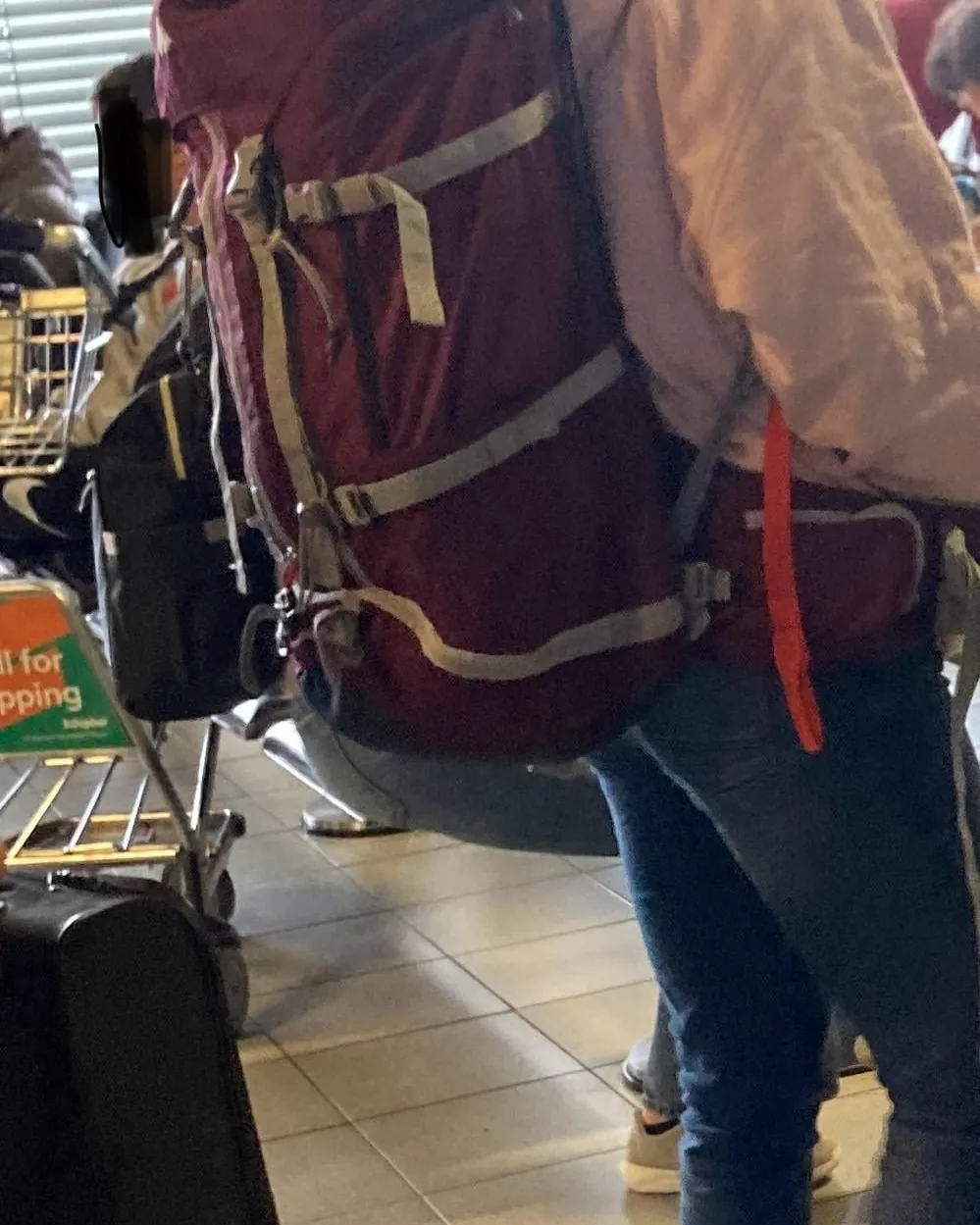 A relaxed traveler sitting with their carry on backpack in an airport lounge.
