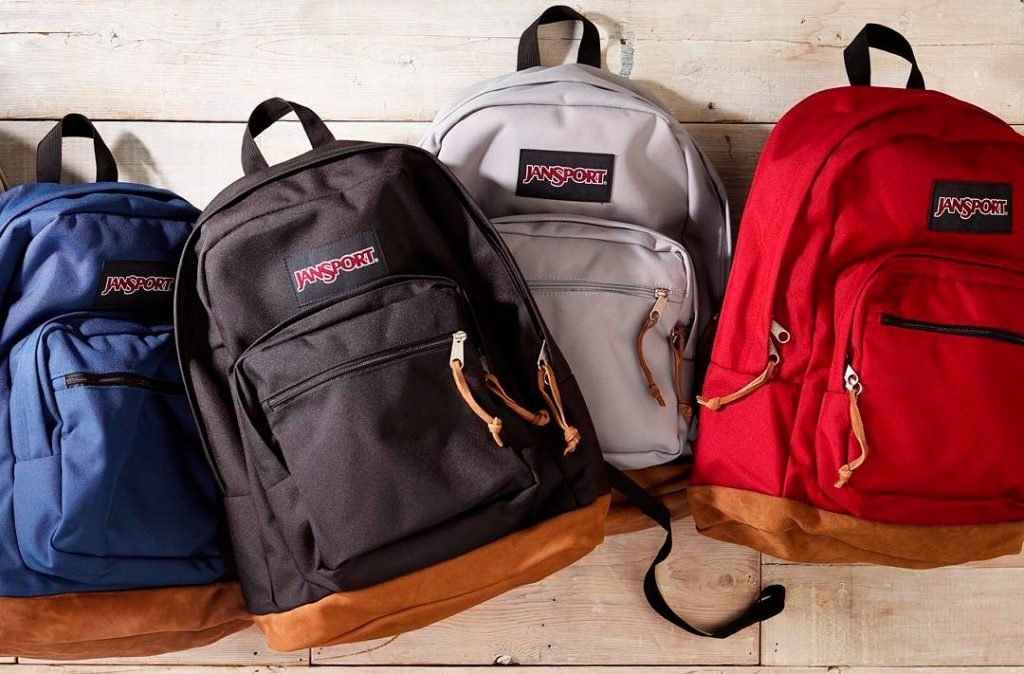 A stylish Jansport backpack rests on a school hallway bench in natural light.