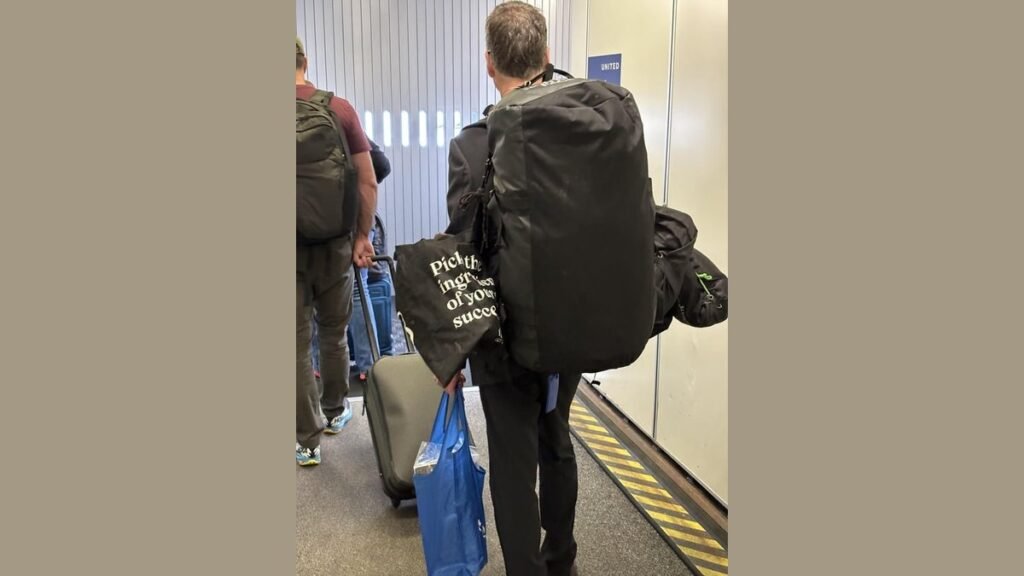 A traveler with a carry-on suitcase and backpack at an airport terminal.