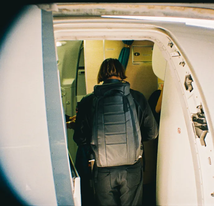 A traveler checks their phone while waiting at the airport with their personal items.