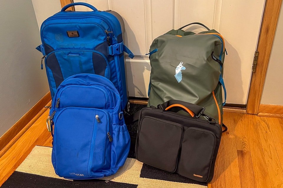 A traveler navigating an airport terminal with a backpack and a carry-on bag.