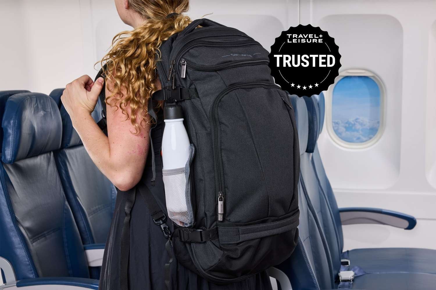 A traveler checking details about the best backpack for travelling at a desk.