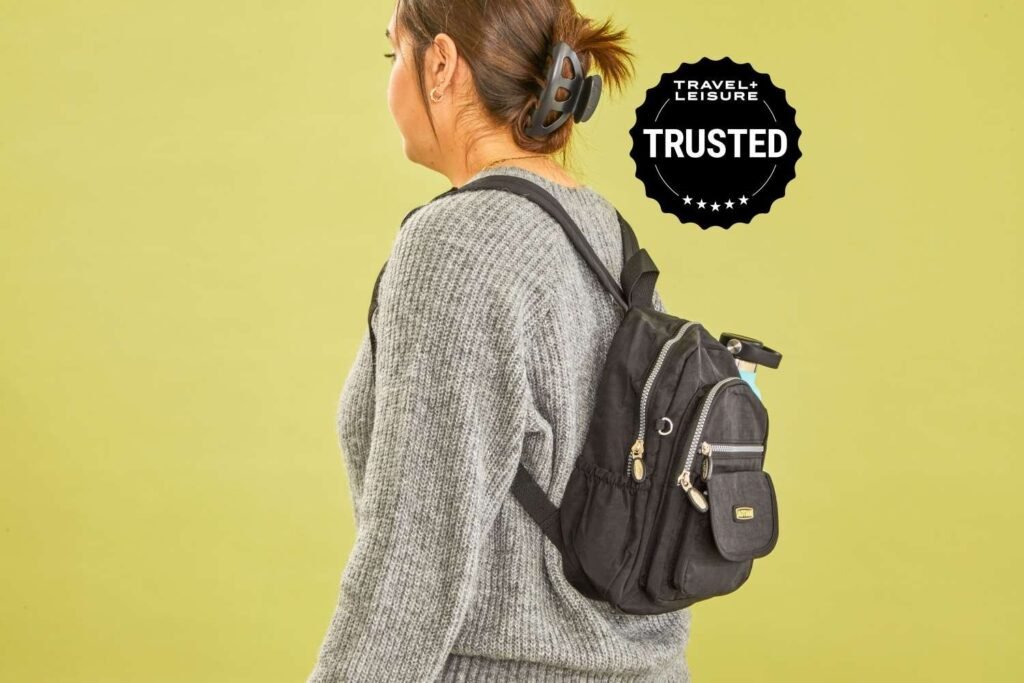 A sleek leather mini backpack displayed on a minimalist surface in soft natural light.