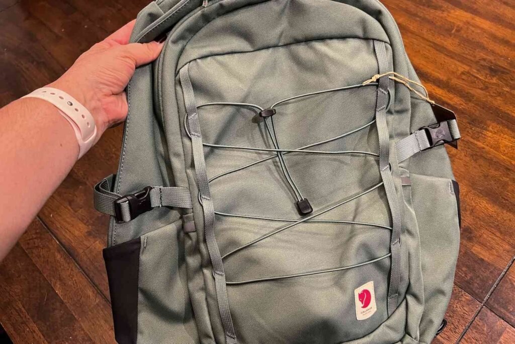 A stylish modern backpack resting on a wooden bench in a sunlit park.