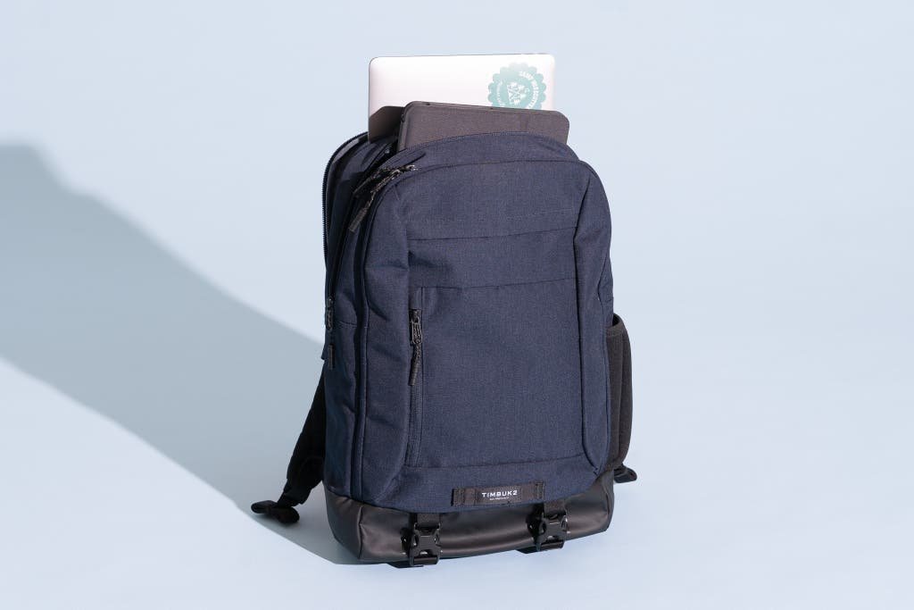 A dark gray travel backpack resting on an airport terminal floor.