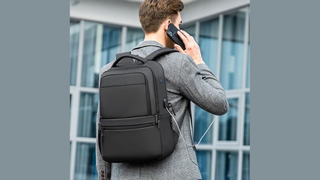 A dark grey business travel backpack sits on an airport bench.