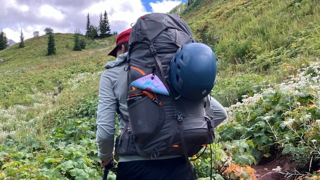 A durable camping backpack sitting on a mossy rock in a lush forest.