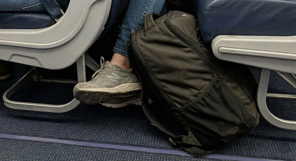A person compressing a soft-sided 40L travel backpack to fit into a sizing frame.