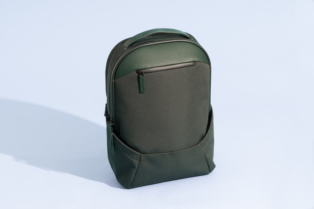 Stylish women's computer backpack on wooden desk beside silver laptop