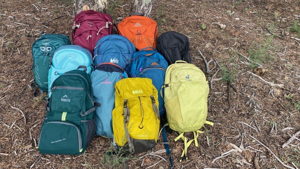 A trekking backpack for women sits on a mossy forest rock.
